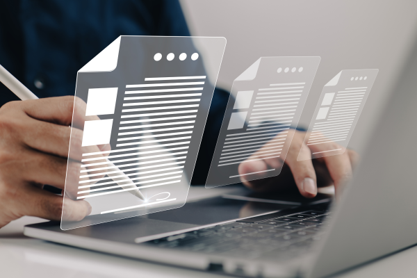 Close-up of hands typing on a laptop with translucent digital document icons floating above the keyboard, symbolizing modern digital workflow or data management